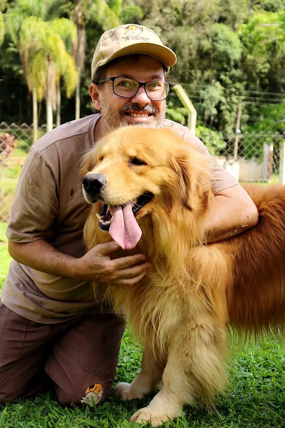 Criador abraçando um Golden Retriever adulto sorridente